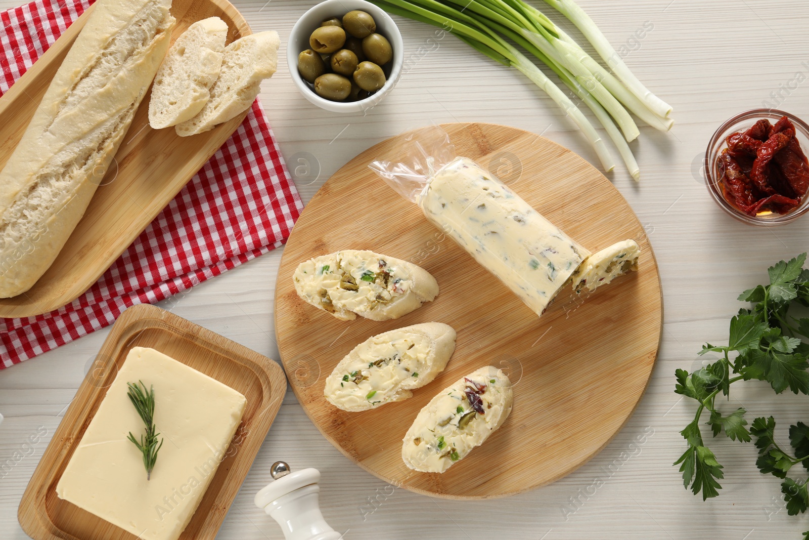 Photo of Tasty butter, bread and other ingredients on wooden table, flat lay