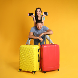 Photo of Happy couple with suitcases and passports for summer trip on yellow background. Vacation travel