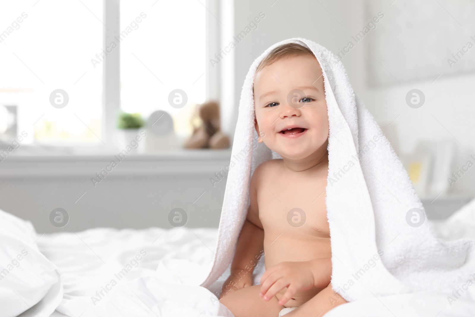 Photo of Adorable little baby with towel on bed at home