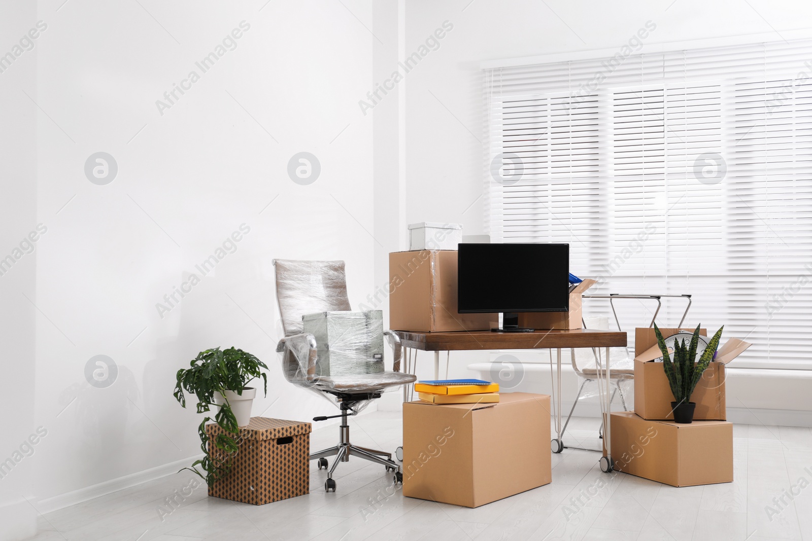 Photo of Cardboard boxes and packed belongings in office. Moving day