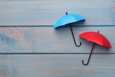 Photo of Small color umbrellas on light blue wooden background, flat lay. Space for text