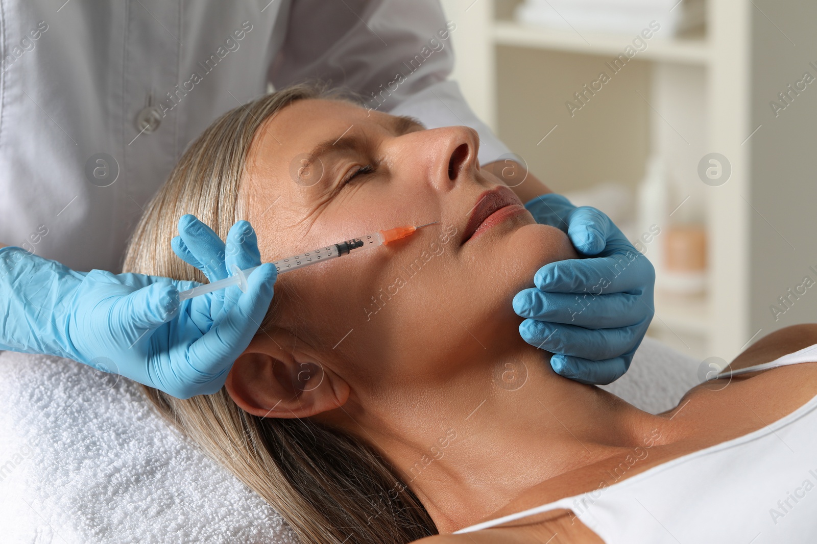 Photo of Doctor giving facial injection to senior woman in clinic, closeup. Cosmetic surgery