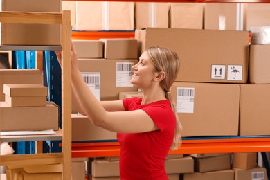 Post office worker near rack with parcels indoors