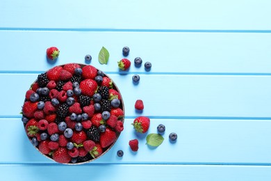 Photo of Different fresh ripe berries on light blue wooden table, flat lay. Space for text