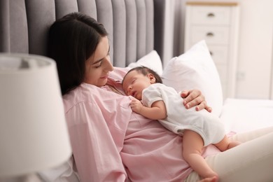 Mother with her sleeping newborn baby in bed at home