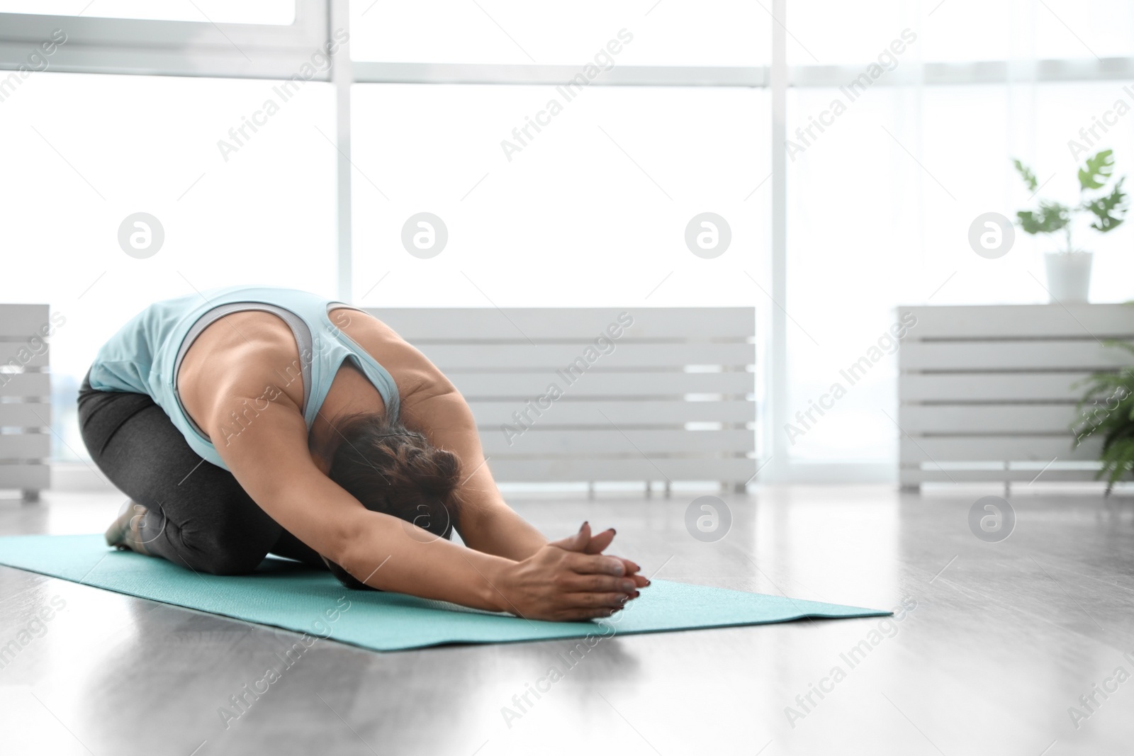 Photo of Young woman practicing extended child's asana pose in yoga studio. Utthita Balasana