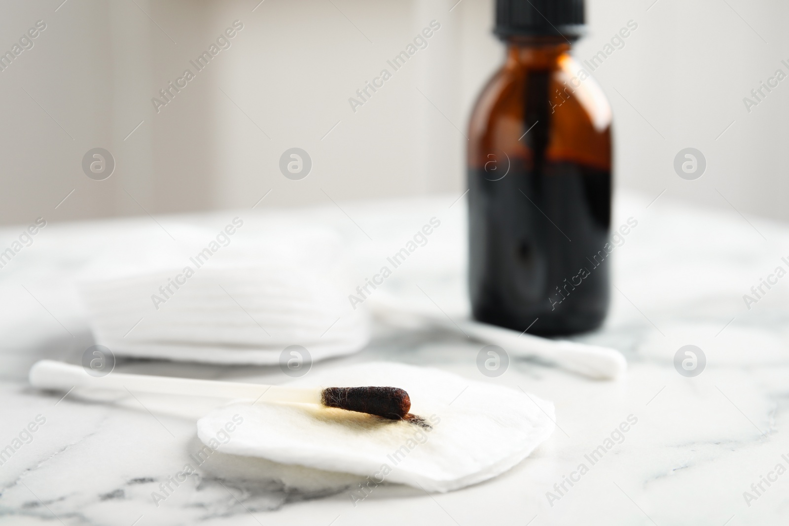 Photo of Cotton bud with medical iodine and pad on white marble table, closeup. Space for text