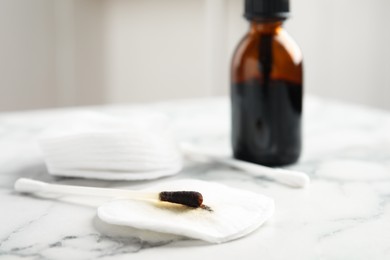 Photo of Cotton bud with medical iodine and pad on white marble table, closeup. Space for text