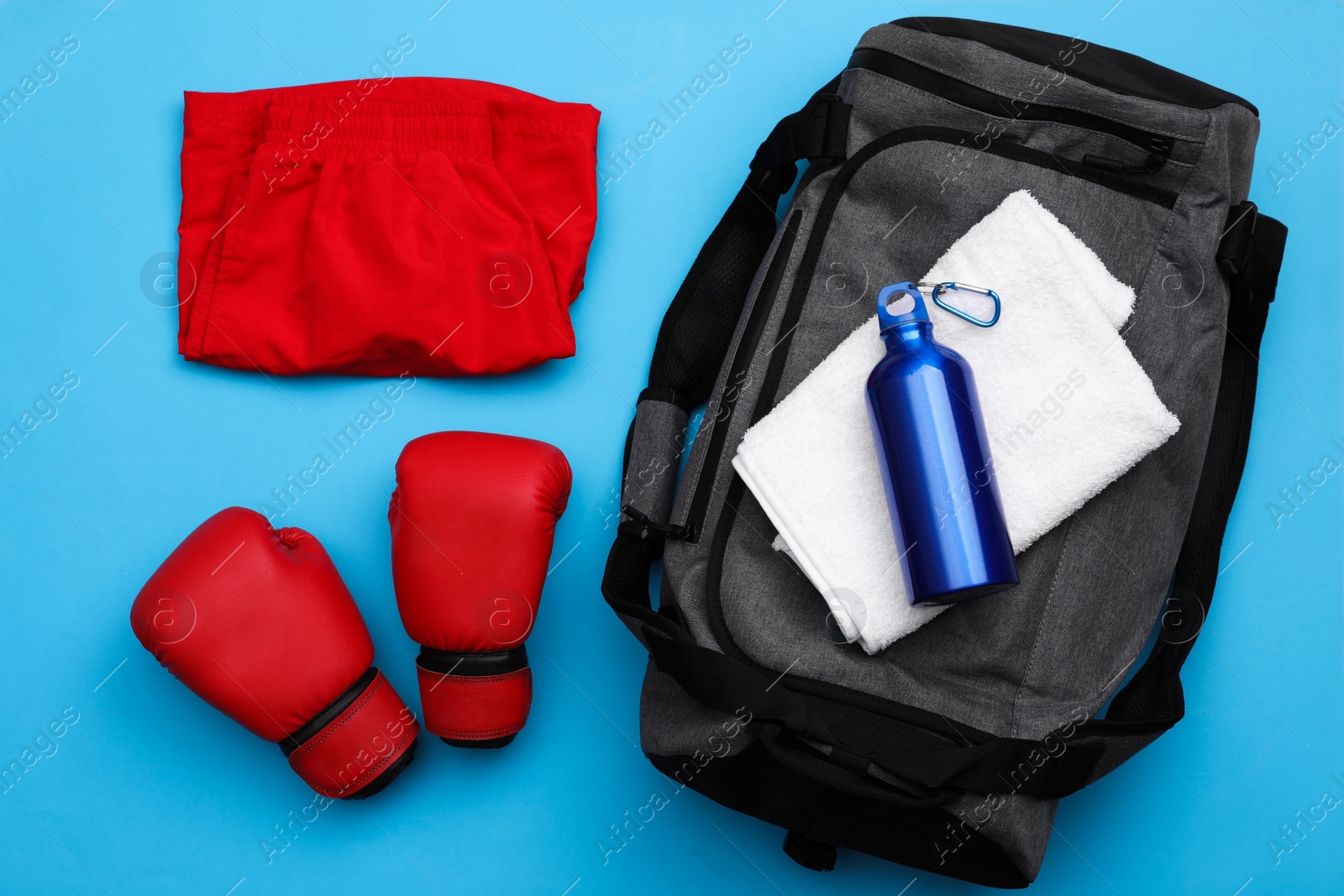 Photo of Gym bag and sports equipment on light blue background, flat lay