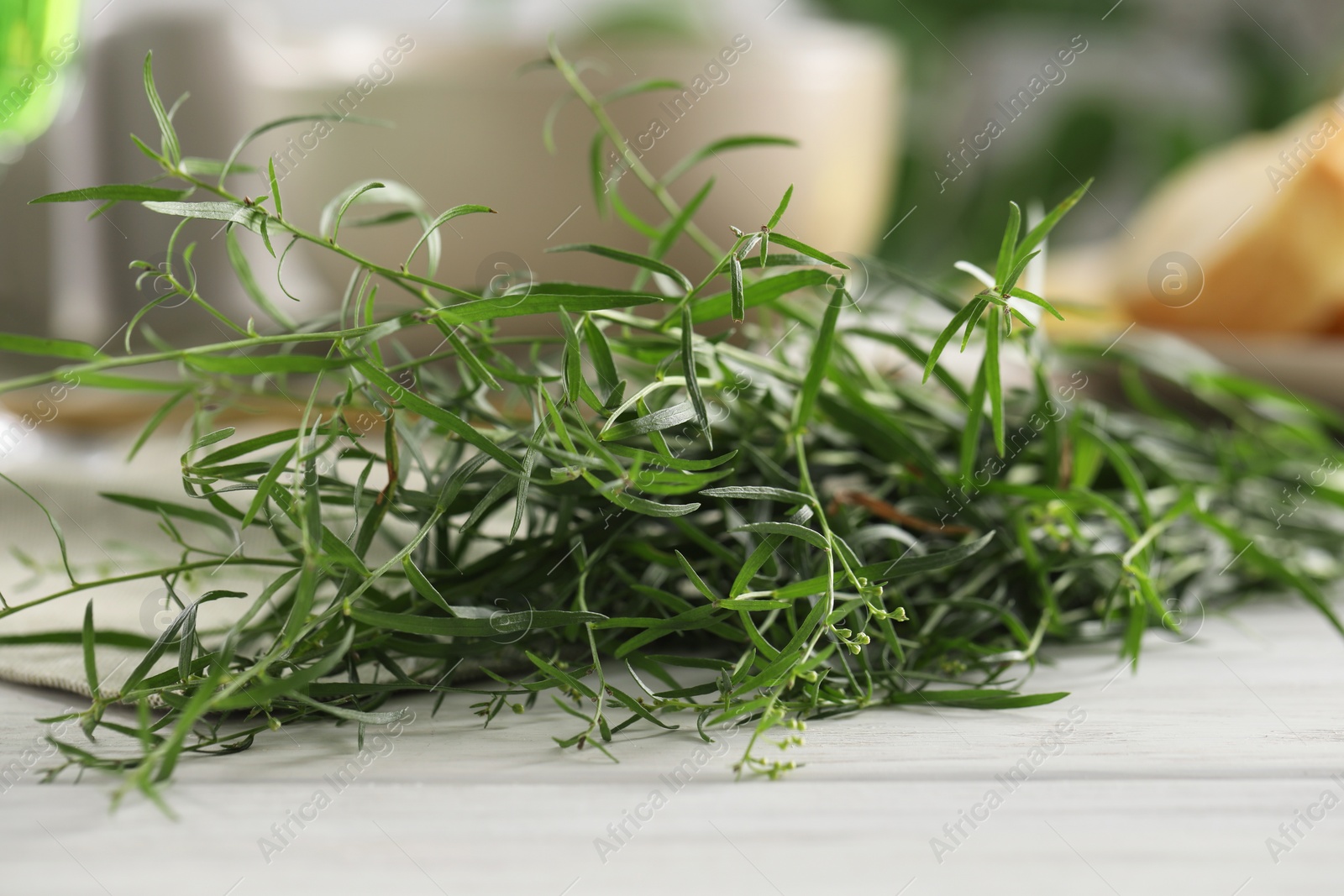 Photo of Fresh tarragon sprigs on white wooden table, closeup