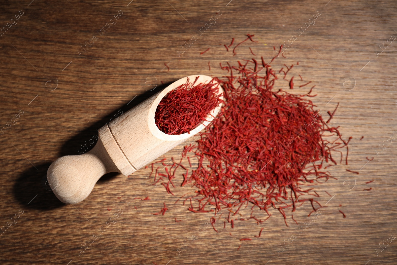 Photo of Aromatic saffron and scoop on wooden table, top view