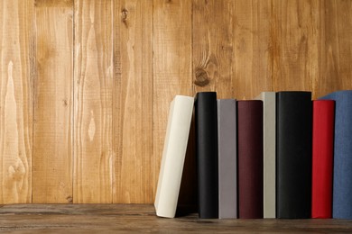 Photo of Stack of hardcover books on wooden table, space for text