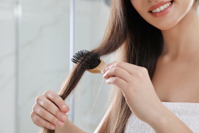 Young woman with hair brush in bathroom, closeup view