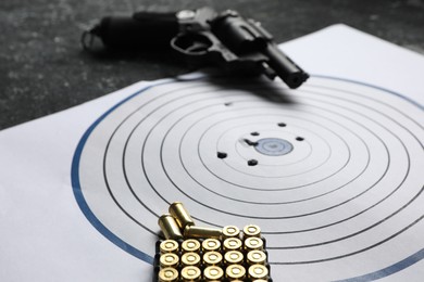 Photo of Shooting target, handgun and bullets on table