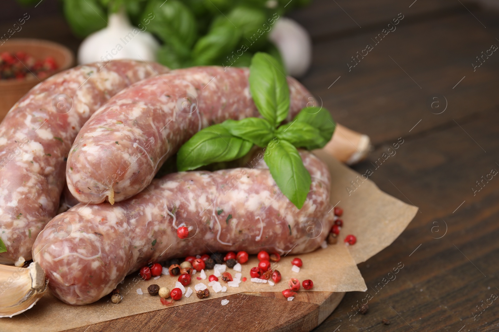 Photo of Raw homemade sausages and different spices on wooden table, closeup. Space for text