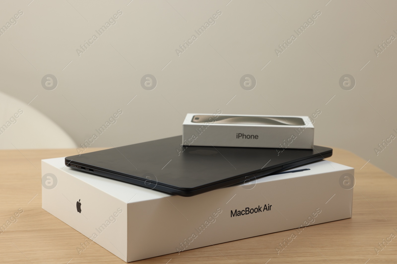 Photo of Leiden, Netherlands - October 6, 2023: Modern black MacBook Air and box from iPhone 15 Pro Max on wooden table