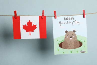 Photo of Happy Groundhog Day greeting card and Canada flag hanging against light background