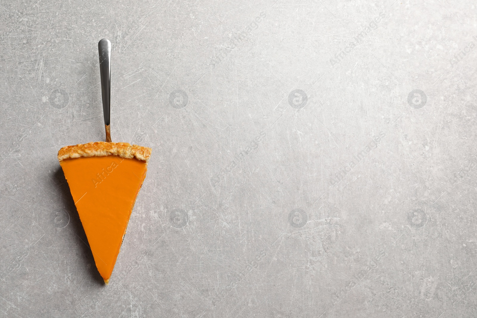 Photo of Piece of fresh delicious homemade pumpkin pie on gray background, top view with space for text