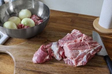 Photo of Fresh raw meat and ripe onions on wooden table