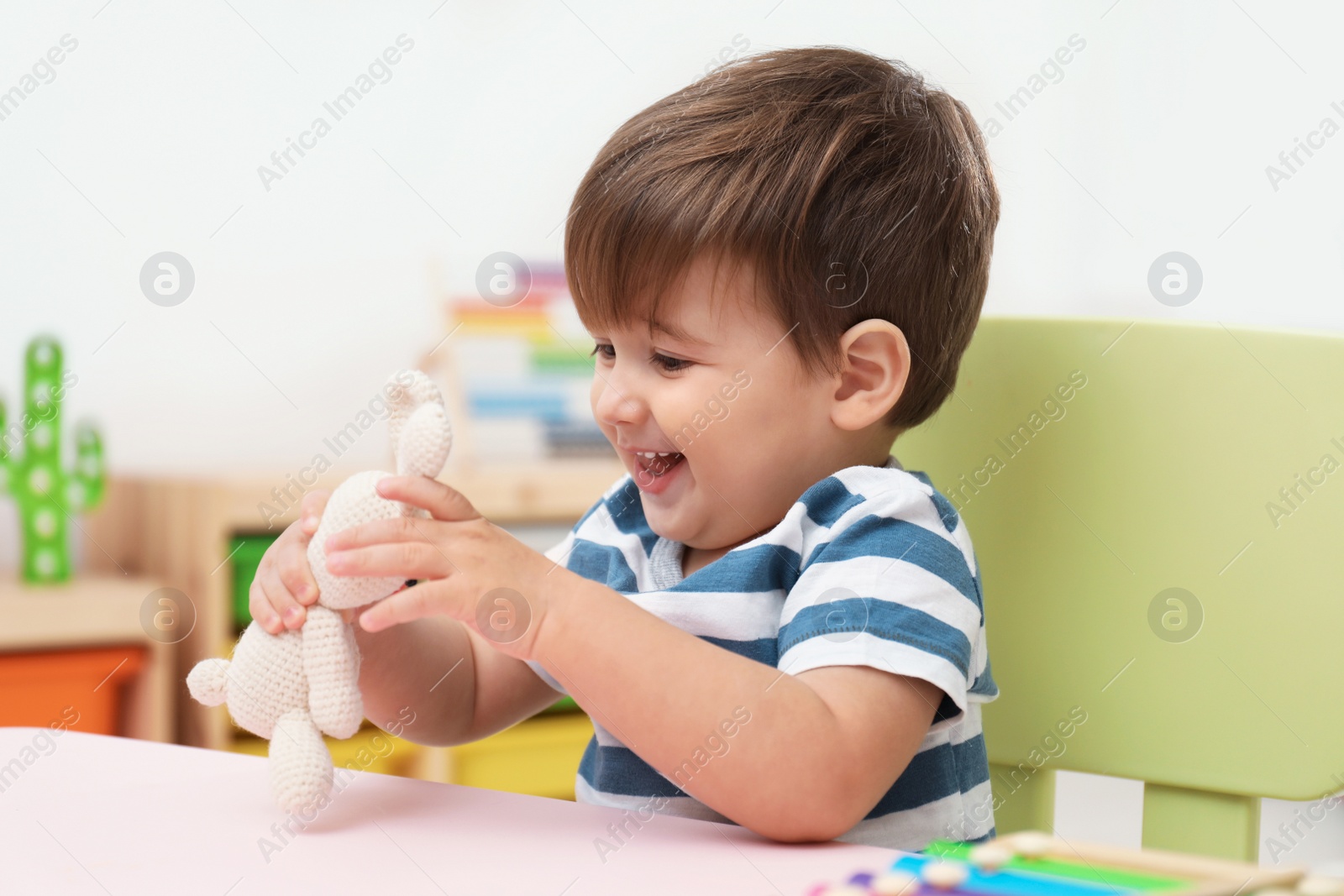 Photo of Little child playing with stuffed bunny at table