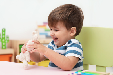 Little child playing with stuffed bunny at table