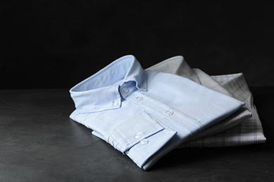 Photo of Stack of classic shirts on dark grey stone table