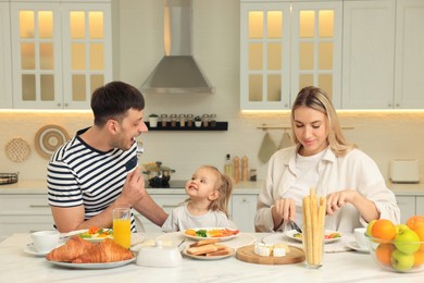 Happy family having breakfast together at table in kitchen