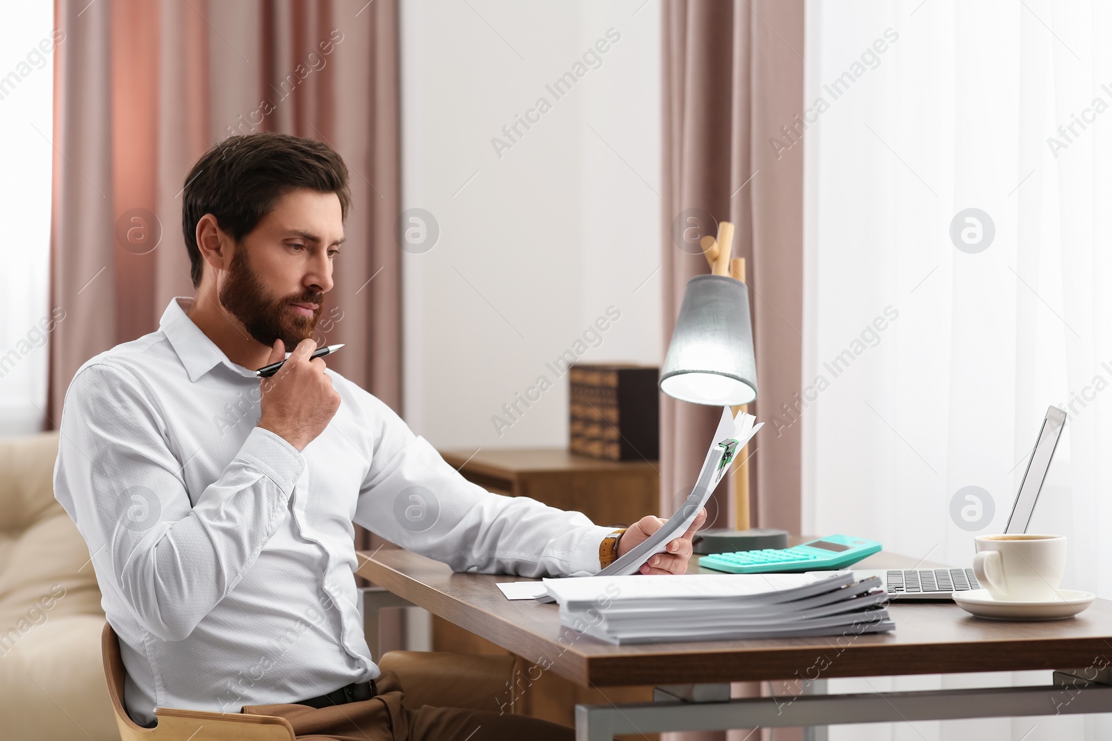 Photo of Businessman working with documents at wooden table in office