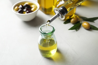 Pouring fresh olive oil into bottle on table