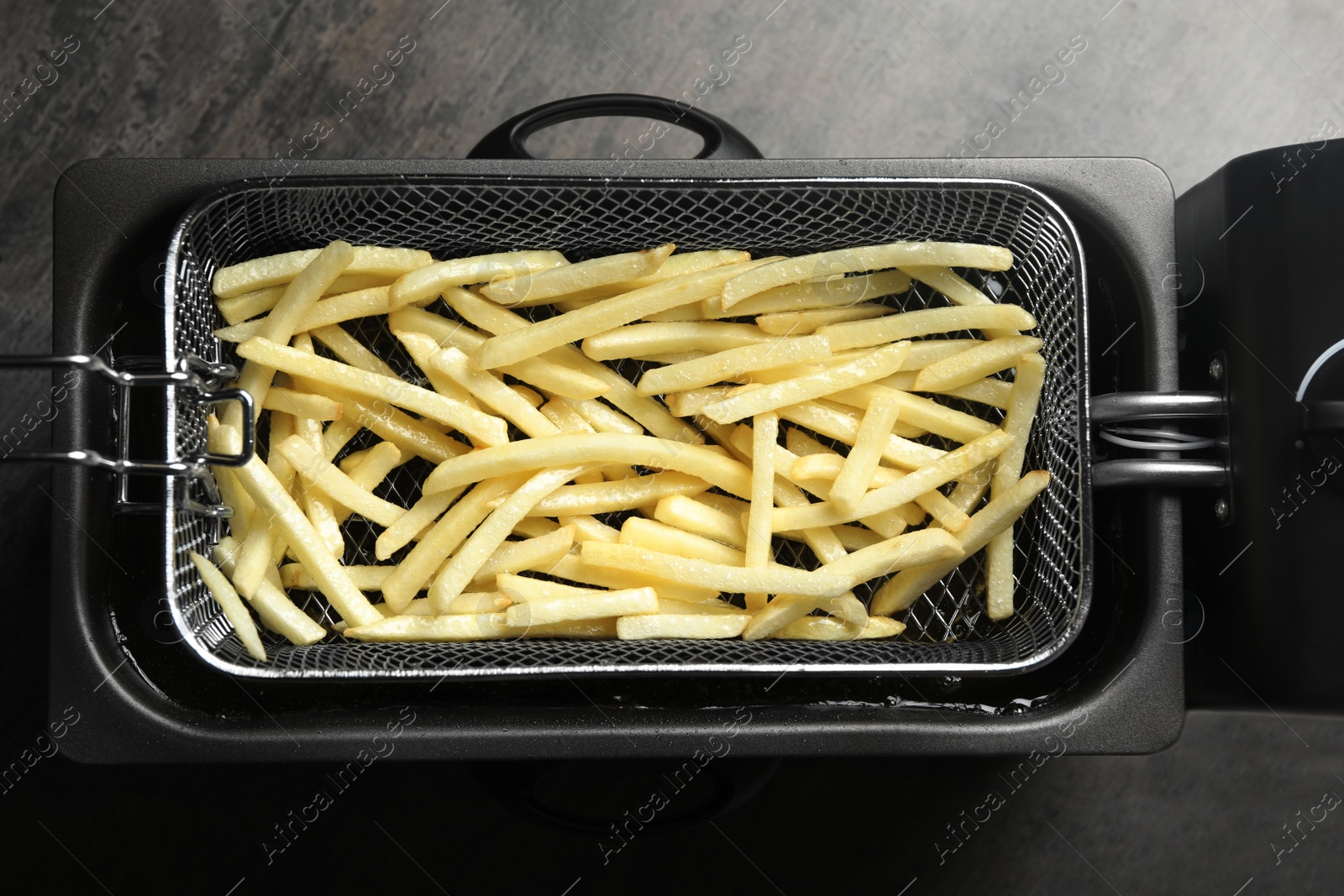 Photo of Cooking delicious french fries in hot oil, top view