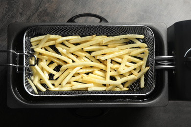 Photo of Cooking delicious french fries in hot oil, top view