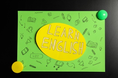 Photo of Sheet of paper with phrase Learn English on blackboard, closeup