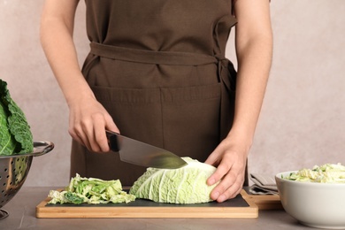 Woman cutting savoy cabbage on board at table