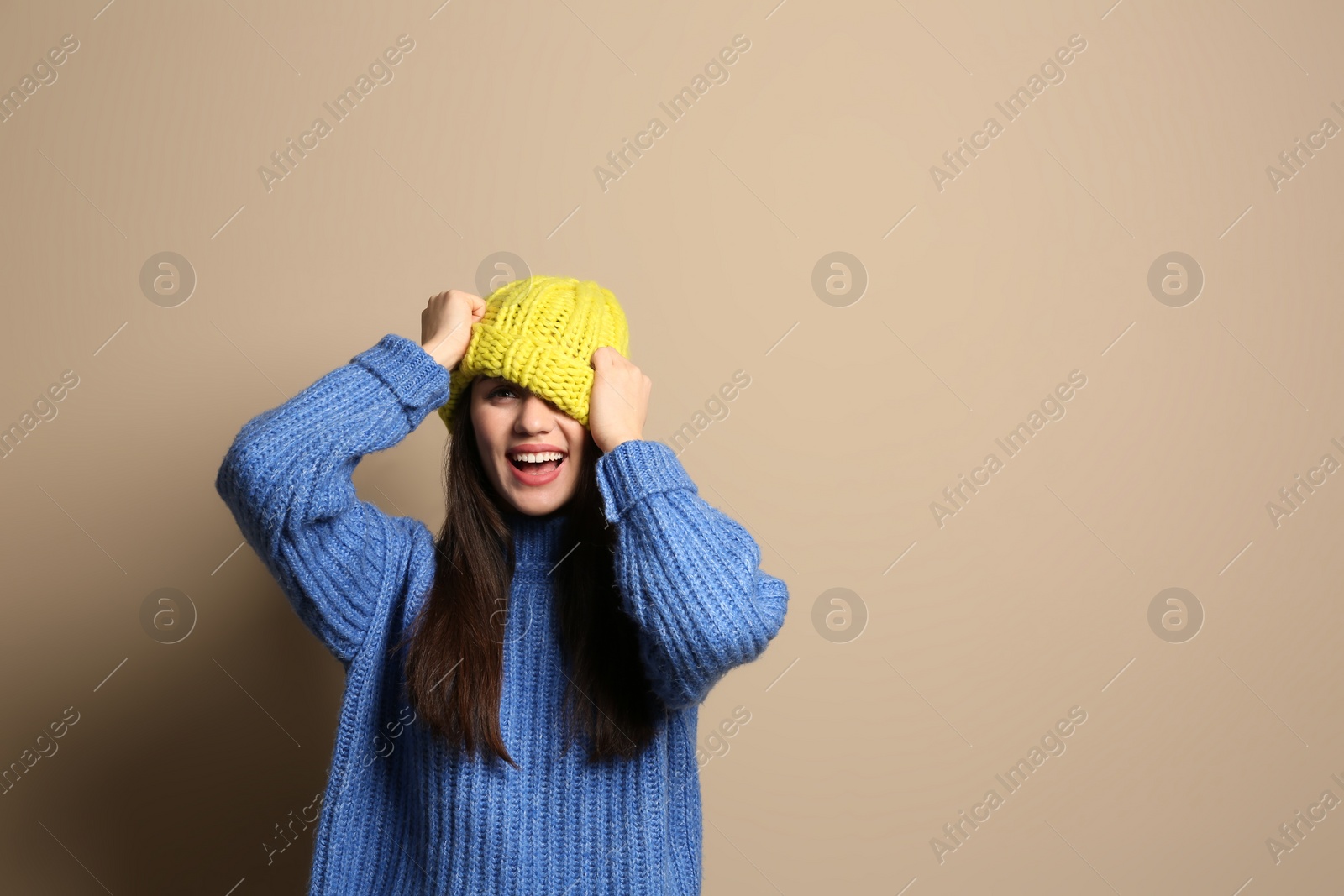 Photo of Young woman wearing warm clothes on color background, space for text. Winter season