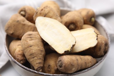 Photo of Whole and cut tubers of turnip rooted chervil in bowl on table, closeup
