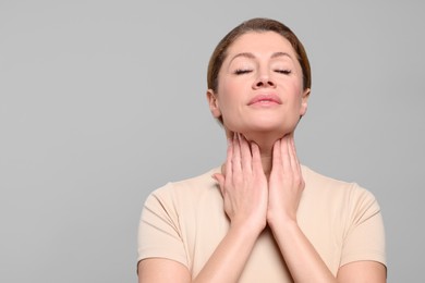 Photo of Woman suffering from sore throat on light grey background. Space for text