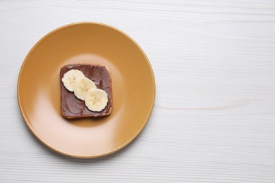Photo of Toast with tasty nut butter and banana on white wooden table, top view. Space for text