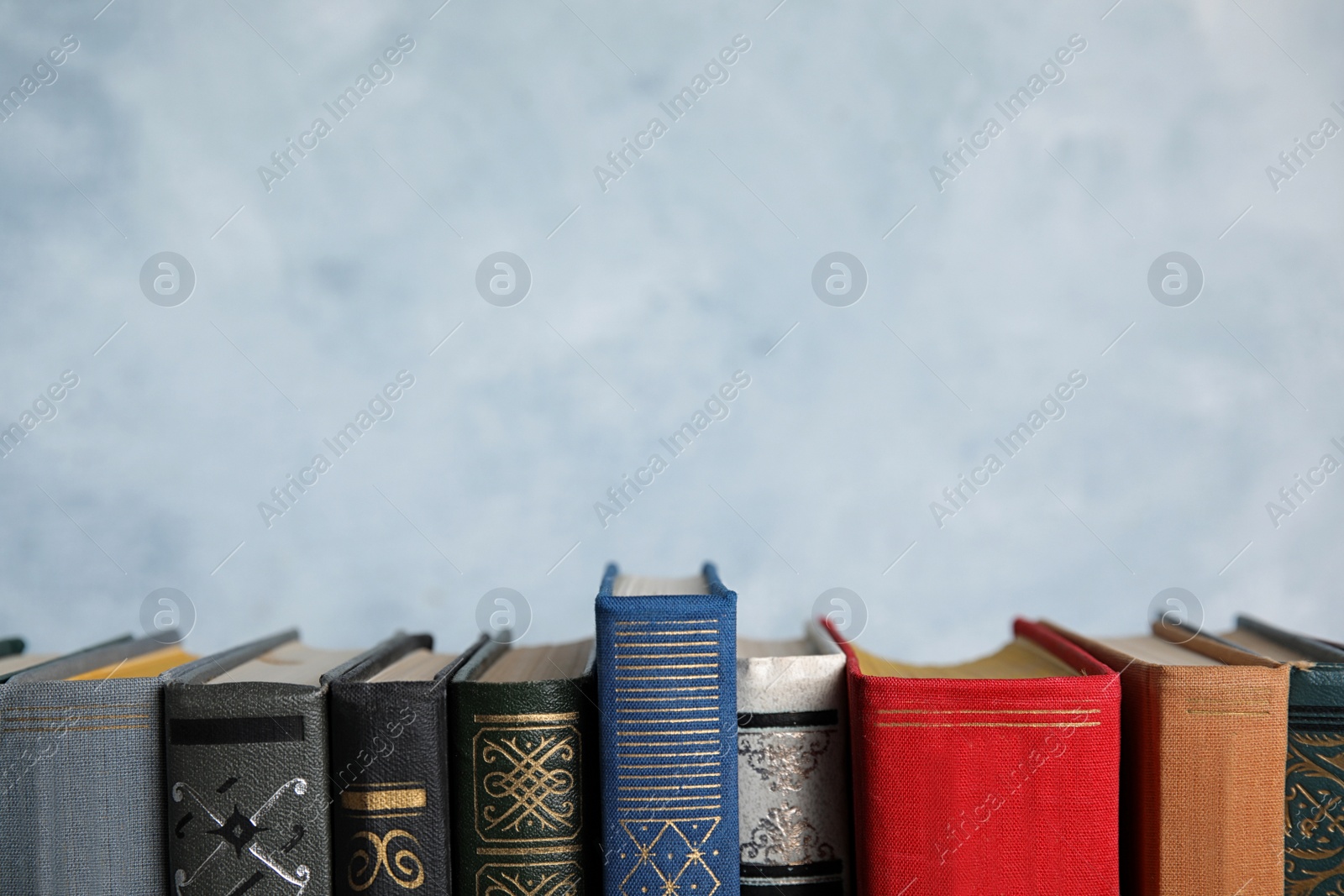 Photo of Stack of hardcover books on light blue background. Space for text