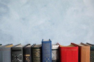 Stack of hardcover books on light blue background. Space for text