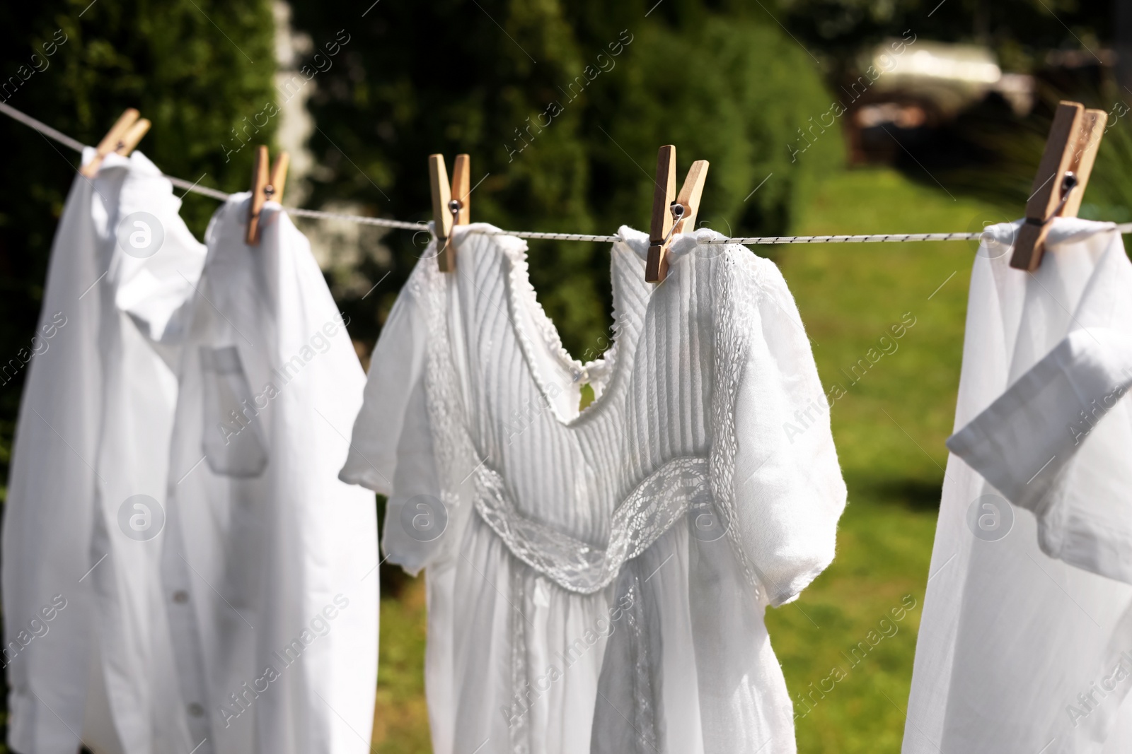 Photo of Clean clothes hanging on washing line in garden. Drying laundry