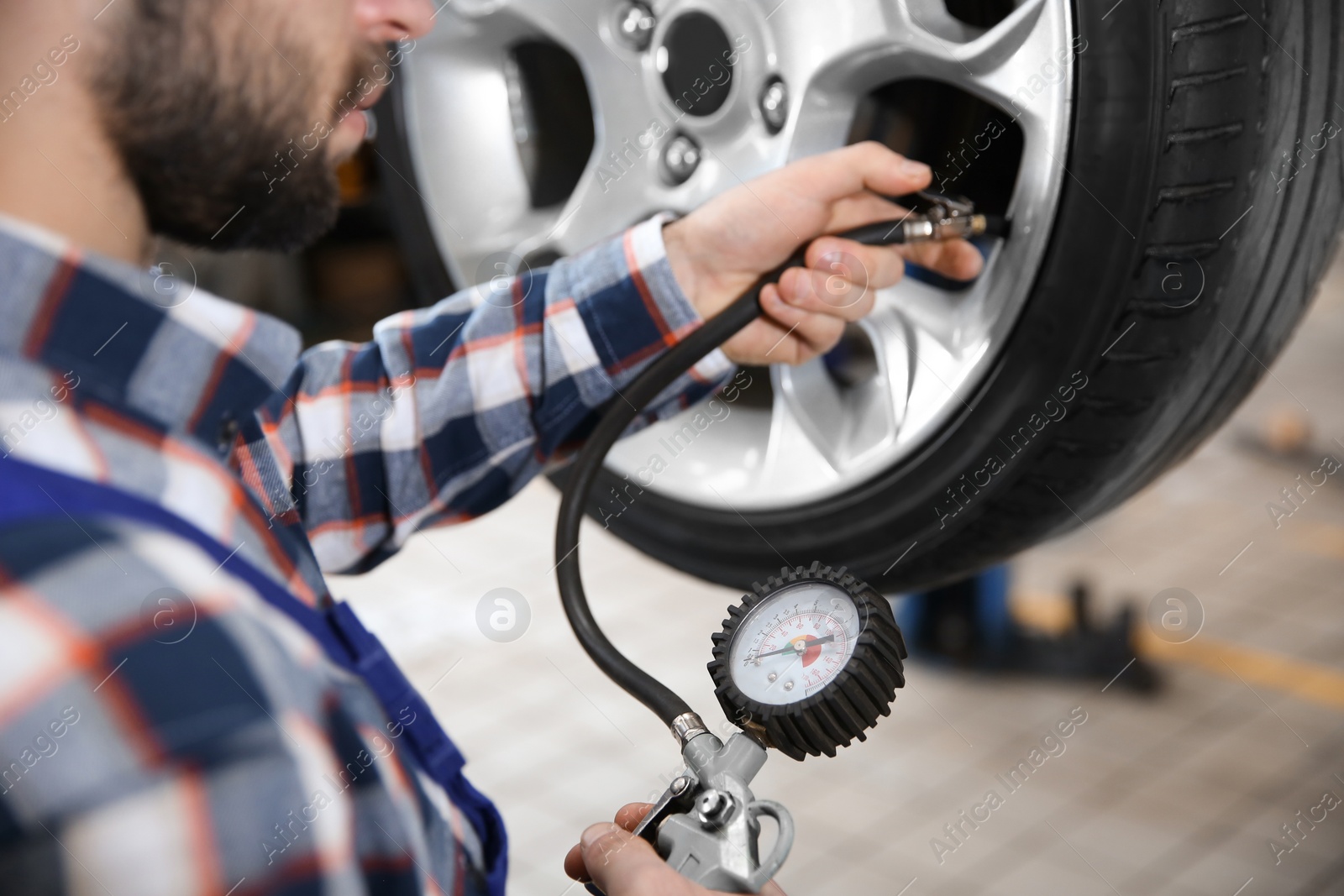 Photo of Mechanic checking tire pressure in service center, closeup