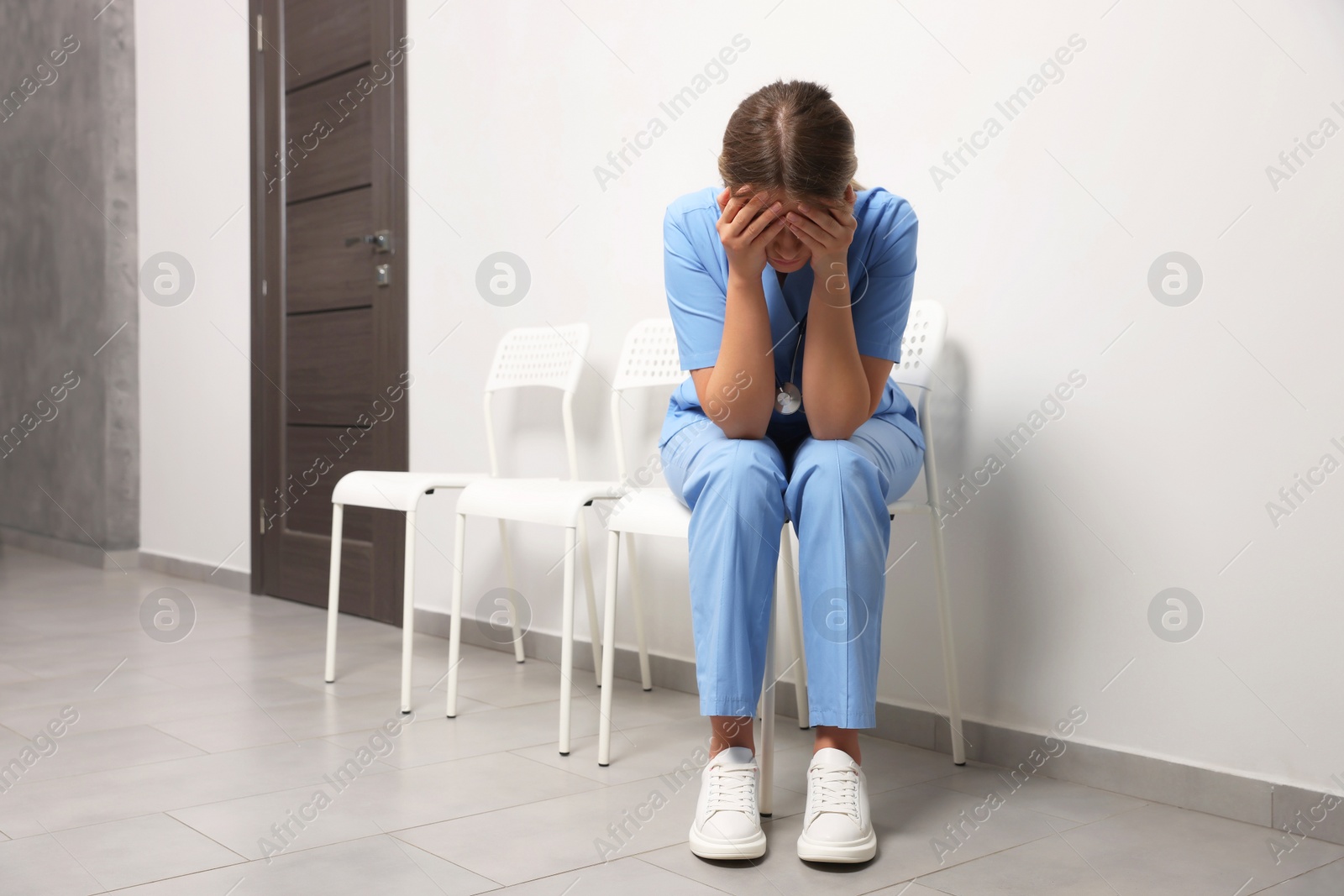 Photo of Exhausted doctor sitting on chair in hospital, space for text