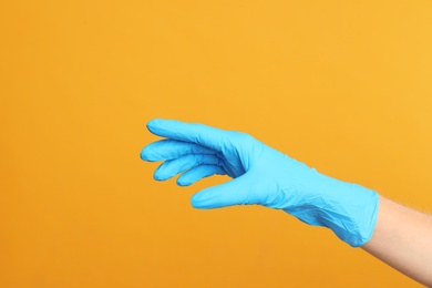 Doctor wearing medical gloves on yellow background, closeup