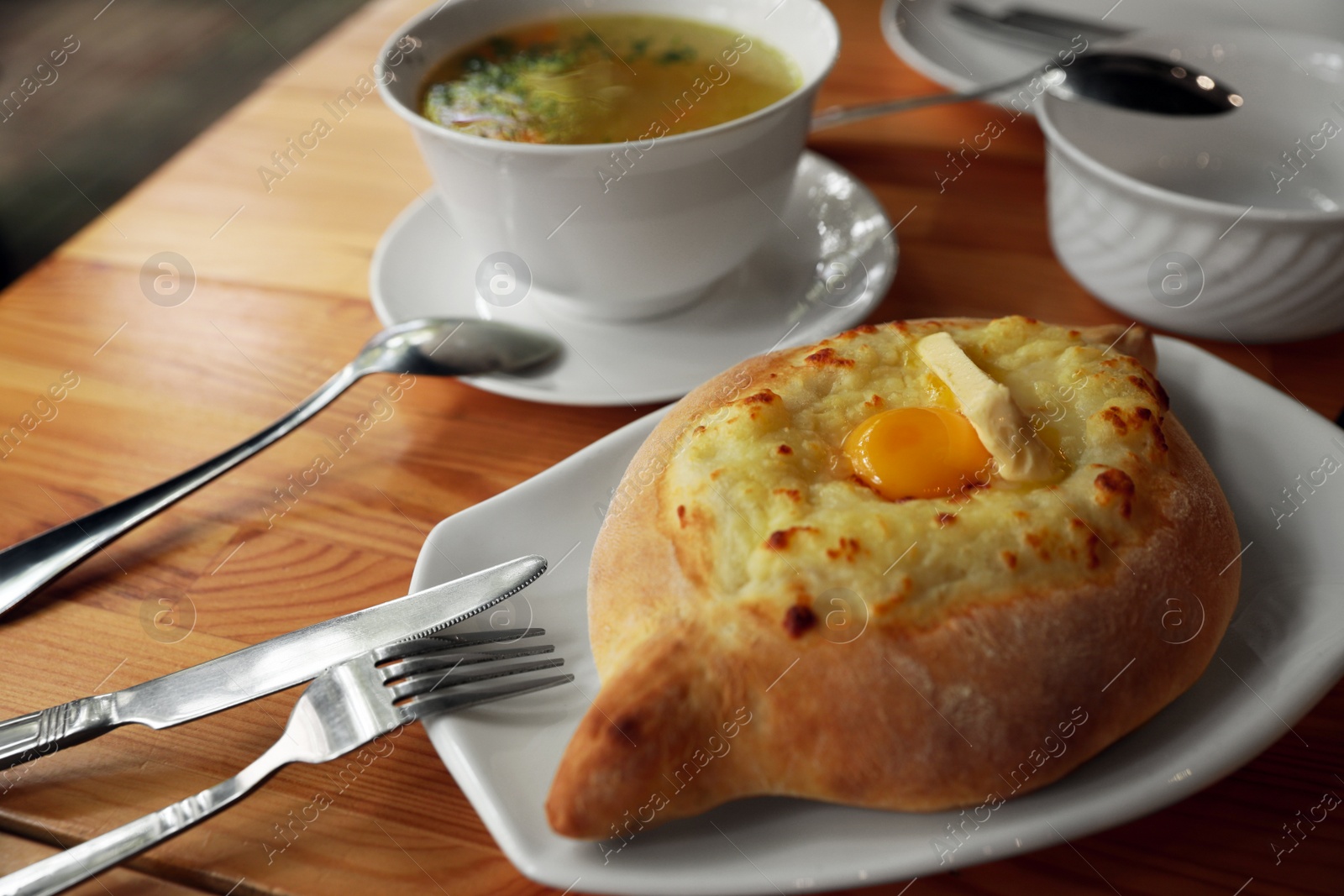 Photo of Fresh delicious Adjarian khachapuri with cheese and egg on wooden table