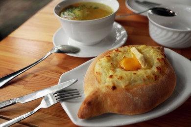 Photo of Fresh delicious Adjarian khachapuri with cheese and egg on wooden table