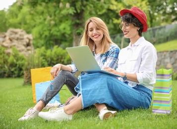 Young women in stylish clothes with laptop outdoors