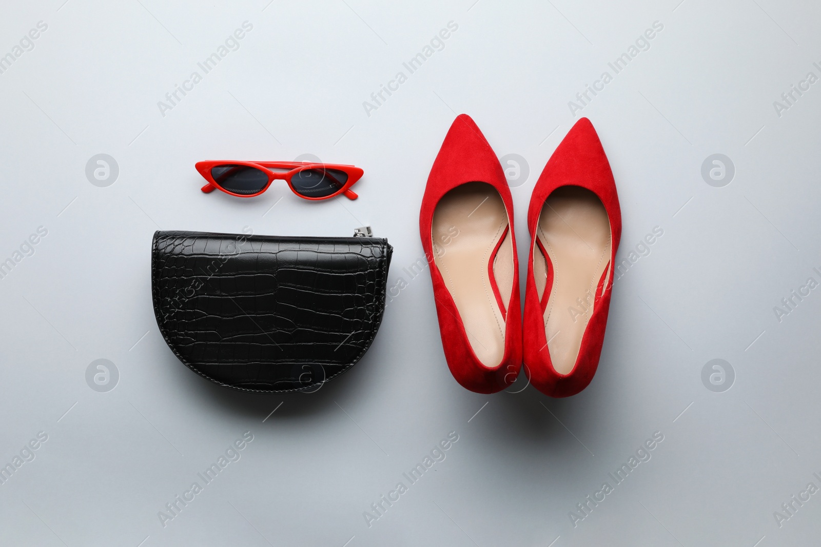 Photo of Stylish woman's bag, sunglasses and shoes on light background, flat lay