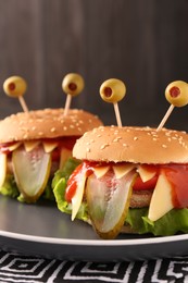Cute monster burgers on table, closeup. Halloween party food