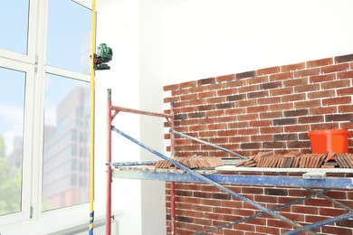 Scaffolding near wall with decorative bricks and tile leveling system indoors