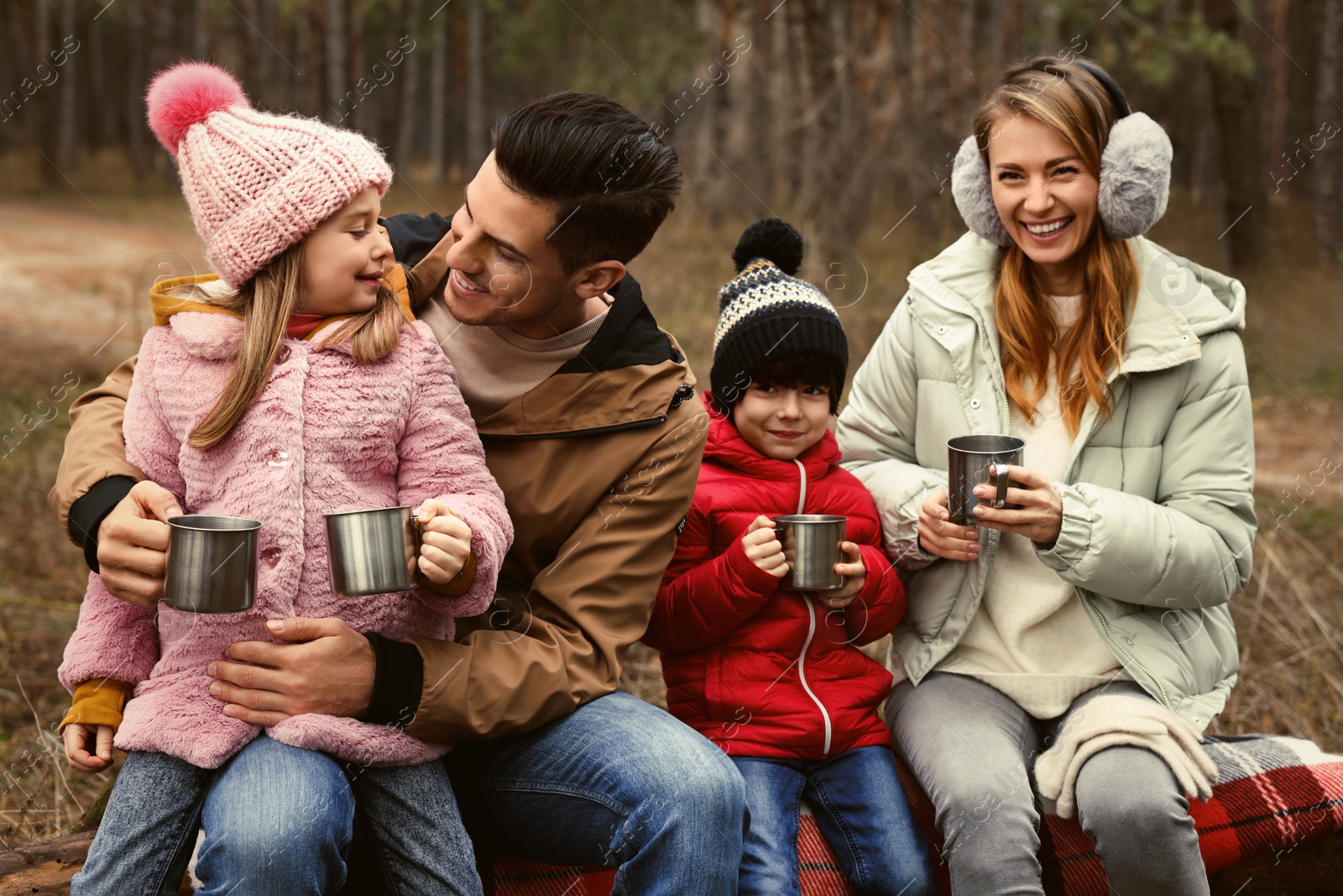 Photo of Happy family with hot drinks spending time together in forest